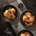 Three plates of ravioli on a black background