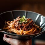 A meaty pasta dish in a black bowl