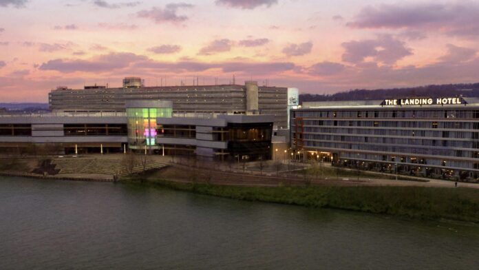 a sunset view from the river of the outside of a large hotel