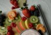 Easiest Fruit Dip A bowl of easiest fruit dip in a light blue bowl on a white quartz surface surrounded by fresh strawberries, blackberries, raspberries, kiwi fruit, mandarin oranges, and apple slices.