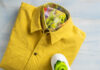 Color Trend: Mellow Yellow A photo of a folded yellow shirt and white sneakers with green socks tucked inside.