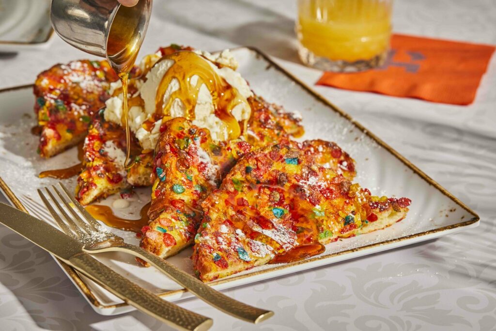 colorful fruity pebbles cover four slices of French toast on a white plate