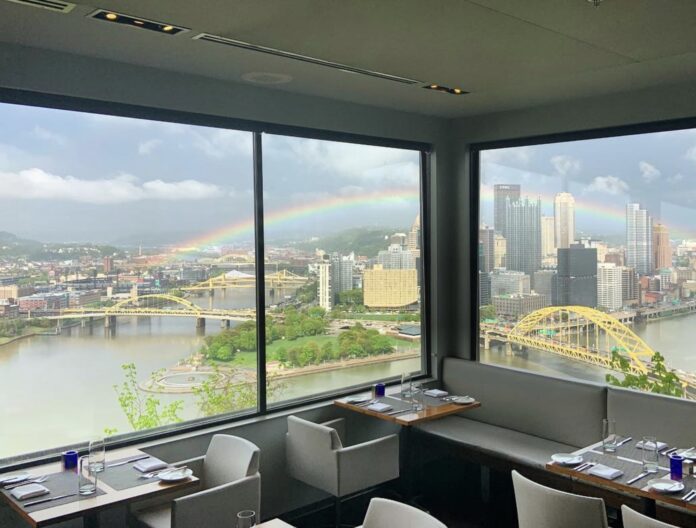 a corner window view from Altius restaurant of Point State Park with a rainbow in the sky