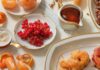 Isfeng Andalusian Donuts Isfeng Andalusian Donuts sit on a plate to the right side of the frame. Oranges and cherries sit to the left.