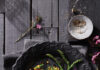 Lentil Asparagus Corn Salad Orange lentil Asparagus Corn Salad sits on a black plate on top of a black wooden table.