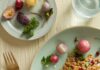 12 Unique Recipes for Radishes in the Spring Roasted Radishes & Farro with Mint Lime Vinaigrette sits on a green plate with a gold fork positioned to the left. A farro dish