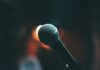 3 Places to Make You Laugh in Pittsburgh A mic against a blurred background. Comedy Shows in Pittsburgh