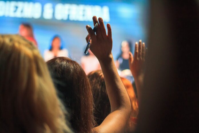 A women raises her hand whole holding a pen during a lecture. Enjoy a lecture at a Pittsburgh institutions.