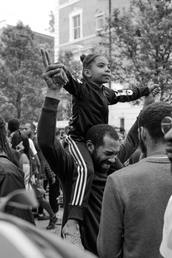 A young Black child sits on their fathers shoulders during a Black music festival