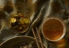 Cucumber Kimchi Cucumber Kimchi in a large bowl with two sticks on top of it. On the side, lies a drink and a small bowl of sliced cucumbers