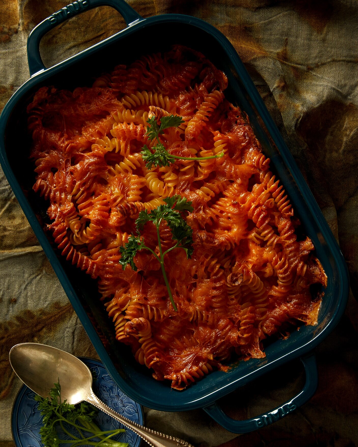 An aerial shot of mac and cheese, orange in color, sitting in a blue casserole dish.