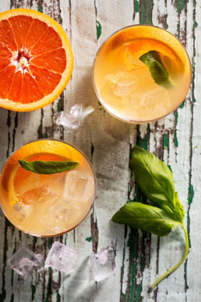 An aerial view of three cello cooler Orangecello cocktails, orange in color. Orangecello cocktail