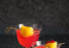Killers of the Flower Moon Cocktail Moon Rising - Killers of the Flower Moon Cocktail. Two sit in martini glasses, garnished with a lemon peel. Bright red in color