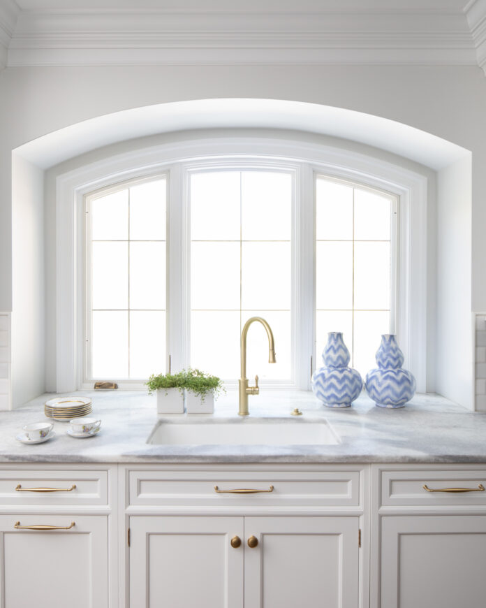 A gold sink faucet surrounded by a white kitchen.