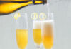 Cognac and Cardamom French 75 3 champagne flutes being filled with Cognac and Cardamom French 75 cocktails on a Cambria surface with a white background