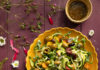 Spiral-Cut Zucchini Summer Salad An aerial shot of a colorful summer salad on a yellow plate sitting on wooden slates purple in color and surrounded by flowers and herbs. Summer Salad Recipe