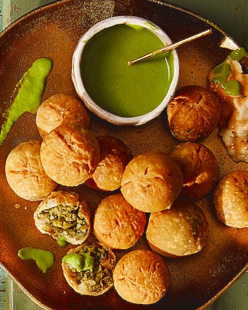 A plate of rolls next to a green sauce, Mint and Cilantro Chutney, in a white bowl. Mint and Cilantro Chutney recipe