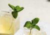 Typical Average Cocktail, Inspired by Ed Sheeran two yellow cocktails in small glass cartons with mint sprig garnish on a white tile surface
