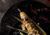 Where to Find Fresh Summer Sweet Corn in Pittsburgh An aerial shot of an ear of spicy mexican street corn sitting on a black plate. Where to Find Fresh Summer Sweet Corn in Pittsburgh