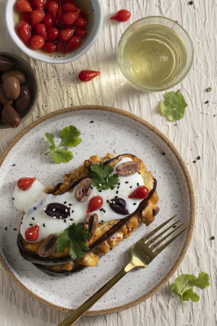 two slices of eggplant with hummus in between and a yogurt sauce with cherry peppers, Kalamata olives, and sesame seeds on top. Low Carb Eggplant Napoleon