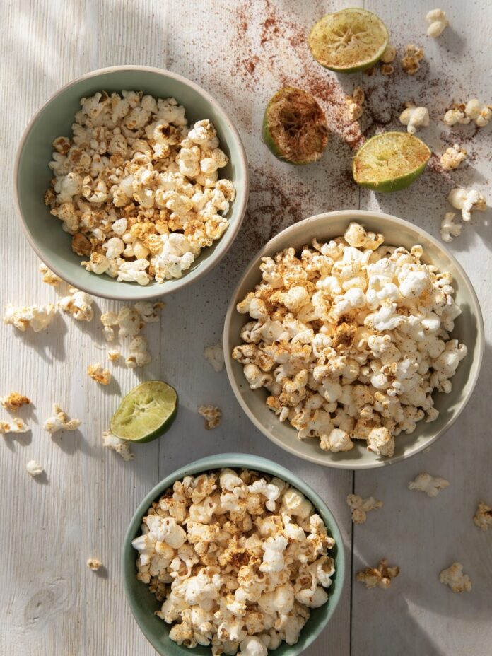 Three bowls of chili-lime popcorn sit on a white table.