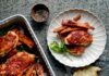 One Pan Spicy Cinnamon Chicken and Carrots A white casserole dish sits with carrots and chicken covered with a redish glaze. To the rights sits a plate with the chicken and carrot recipe.
