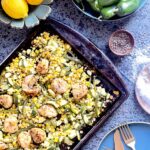 A sheet pan filled with Summer Scallops and Corn. To the side sits bowls of peppers, lemon, and salt. Scallops recipe