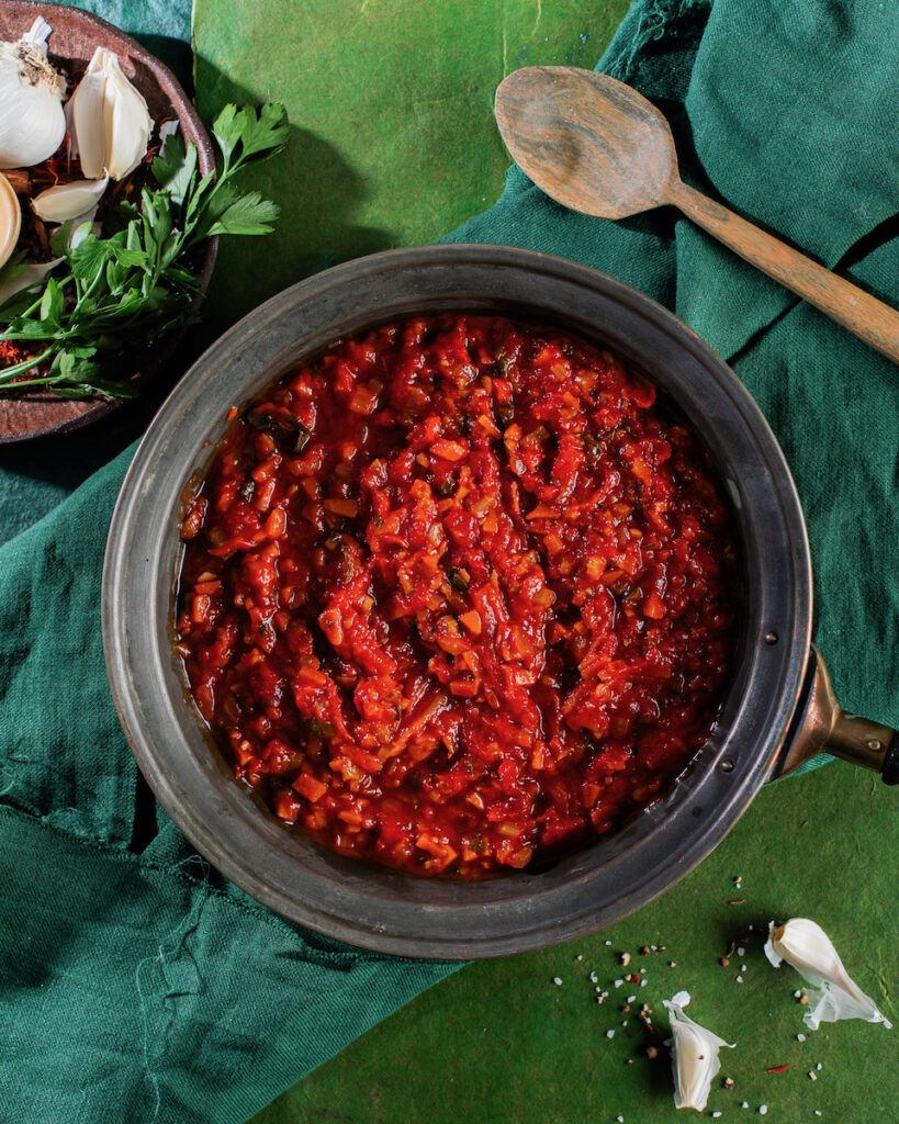 A plate of bright red tomato sauce on a verdant green background