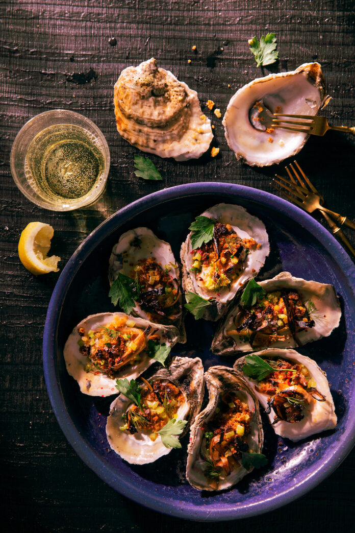 Roasted Oysters with Cornbread, Leek & Banana Pepper Crumble sit in a purple dish with high sides.