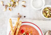 Tomato Strawberry Gazpacho An above shot of Tomato Strawberry Gazpacho, pink-red in color, served in a bowl with three thin breadsticks on the side.