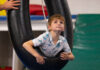 Giving Guide 2023: The Children’s Institute A young boy looking upward in a tire swing at The Children's Institute.