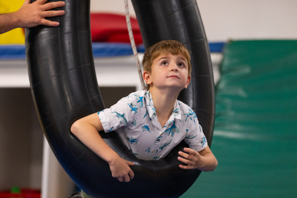 A young boy looking upward in a tire swing at The Children's Institute.