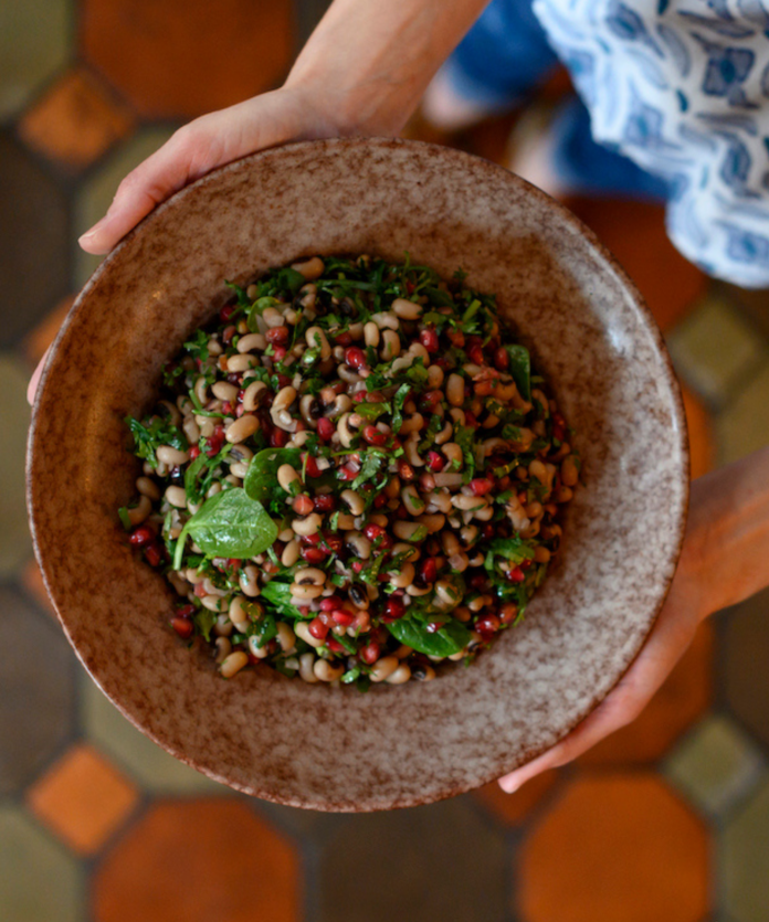 A Sephardic Rosh Hashanah Menu A pair of hands holds a black eyed pea salad, as part of a Sephardic Rosh Hashanah Menu