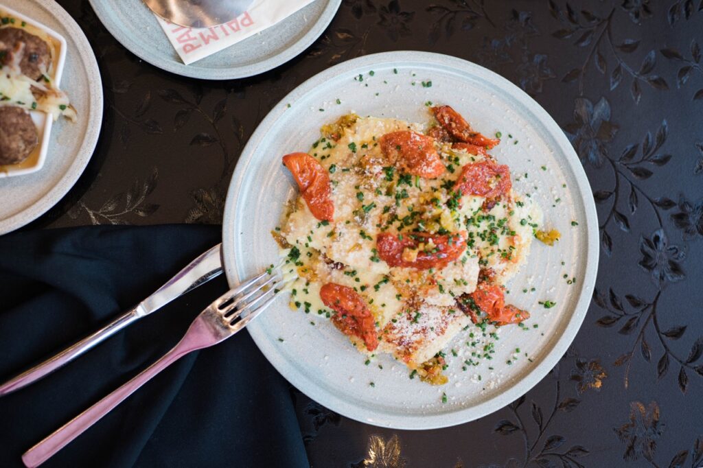 A pasta dish on a lite plate with utensils nearby.