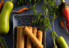 Lumpia with Bottle Gourd and Carrots Flat-lay image of a plate of spring rolls surrounded by colorful vegetables.