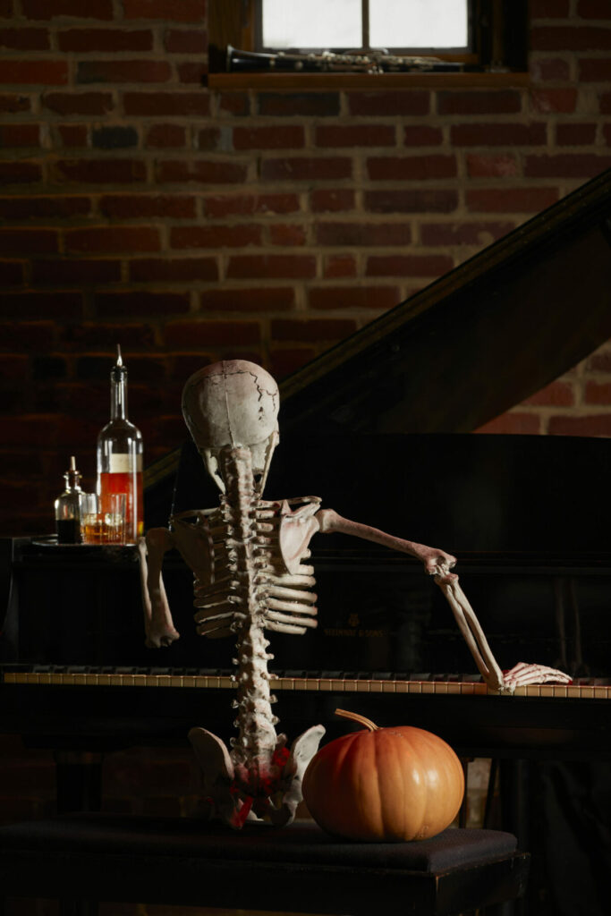 A skeleton sits at a bar with a drink. Halloween drinks