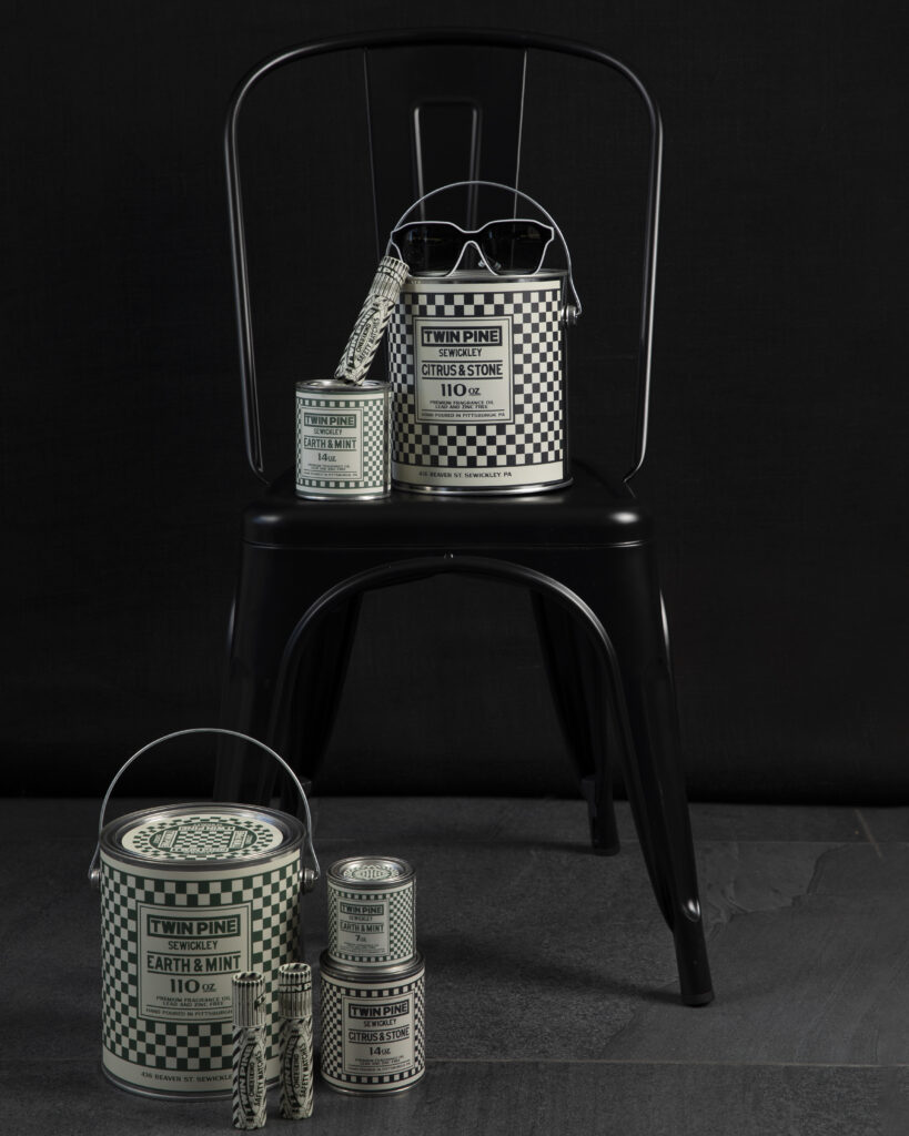Candles in various checkerboard pattern containers are styled around a chair.