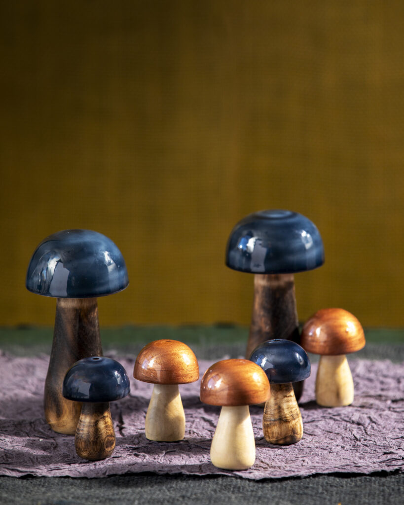 Three brown and four blue wooden mushrooms on a purple mat.