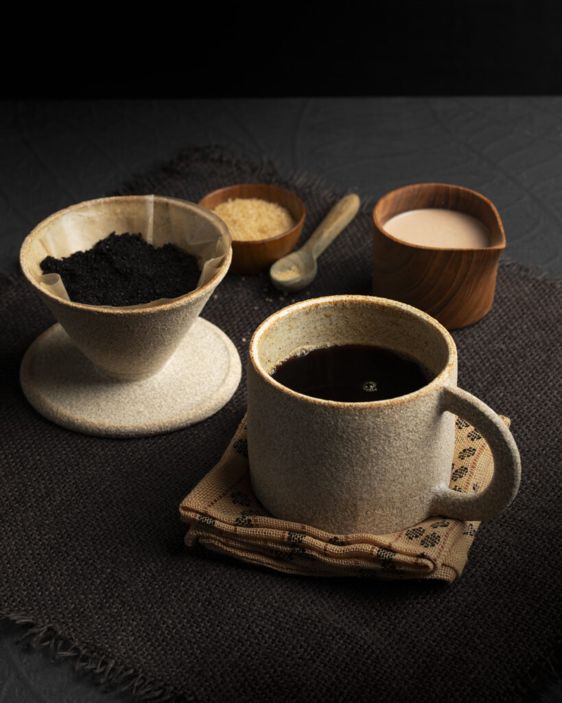 A coffee mug modeled on a table with coffee grounds and milk.