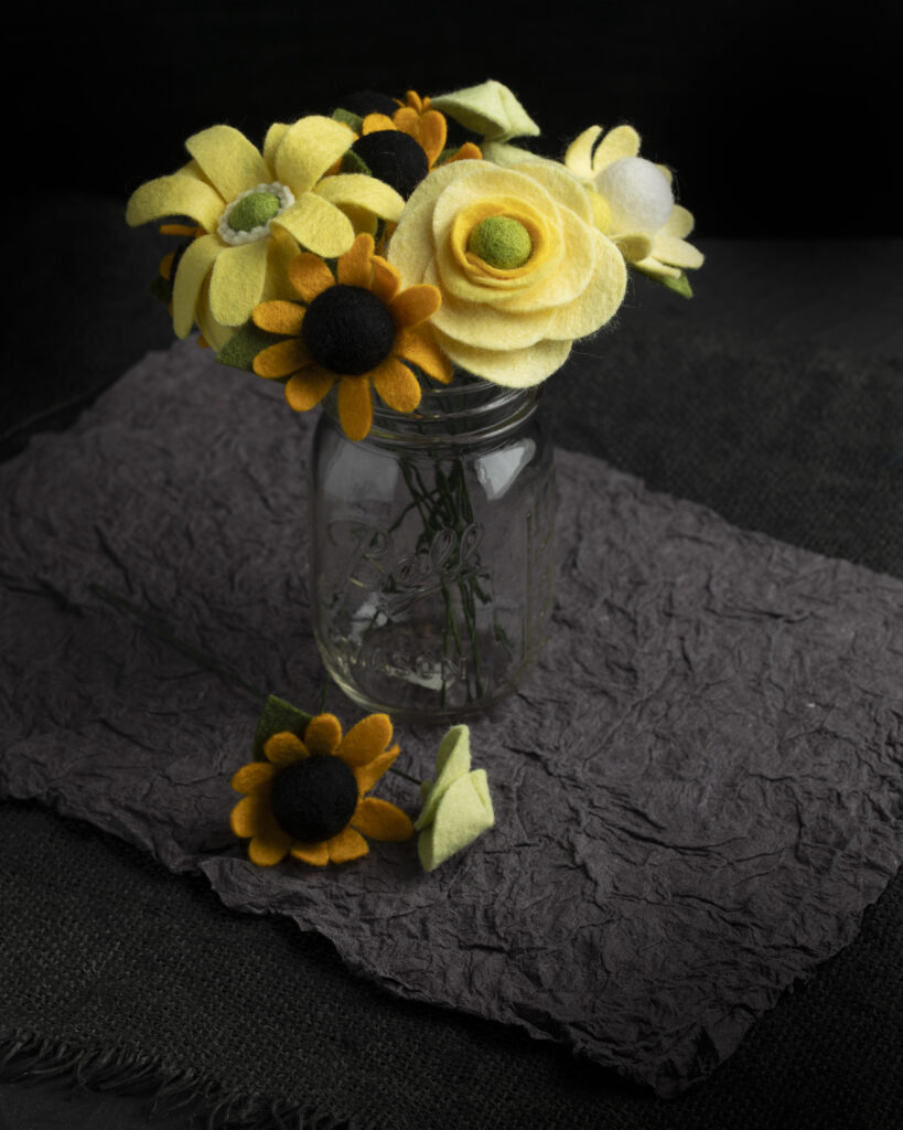 A variety of yellow felt flowers in a vase