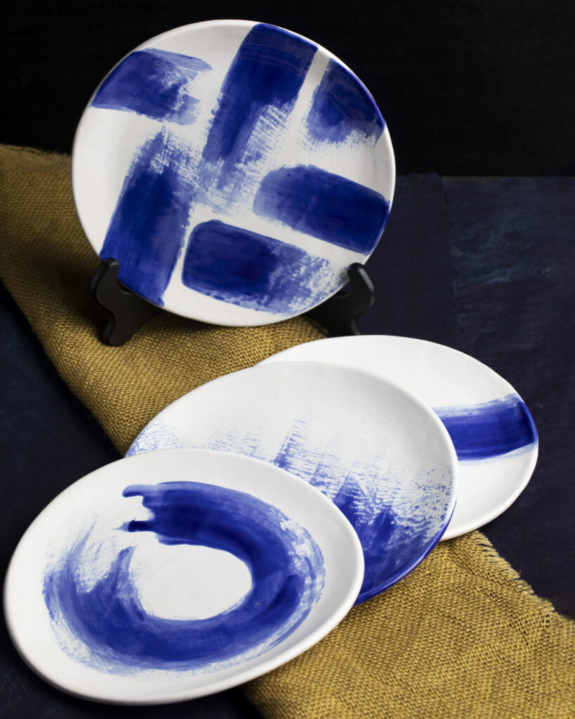 White plates with blue paint streak patterns.