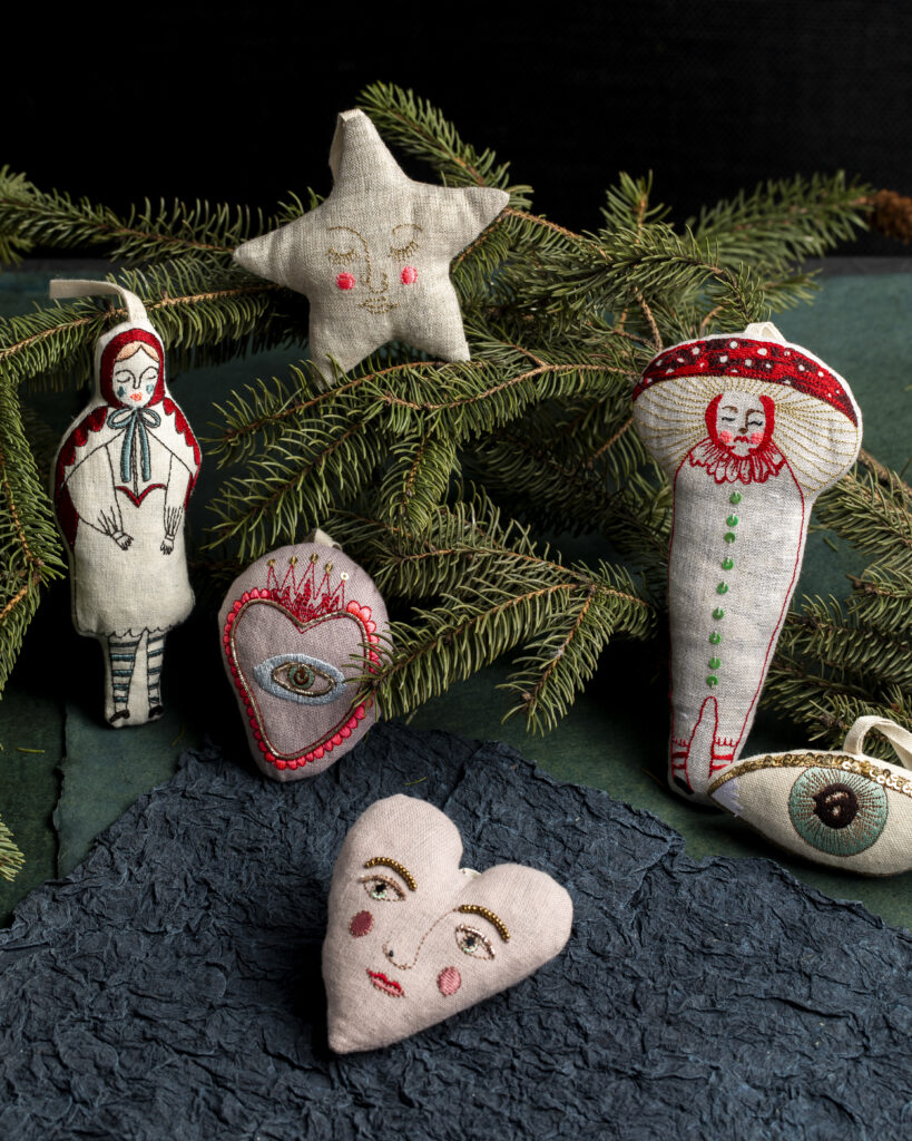 A variety of vintage esc plush ornaments on a pine branch.