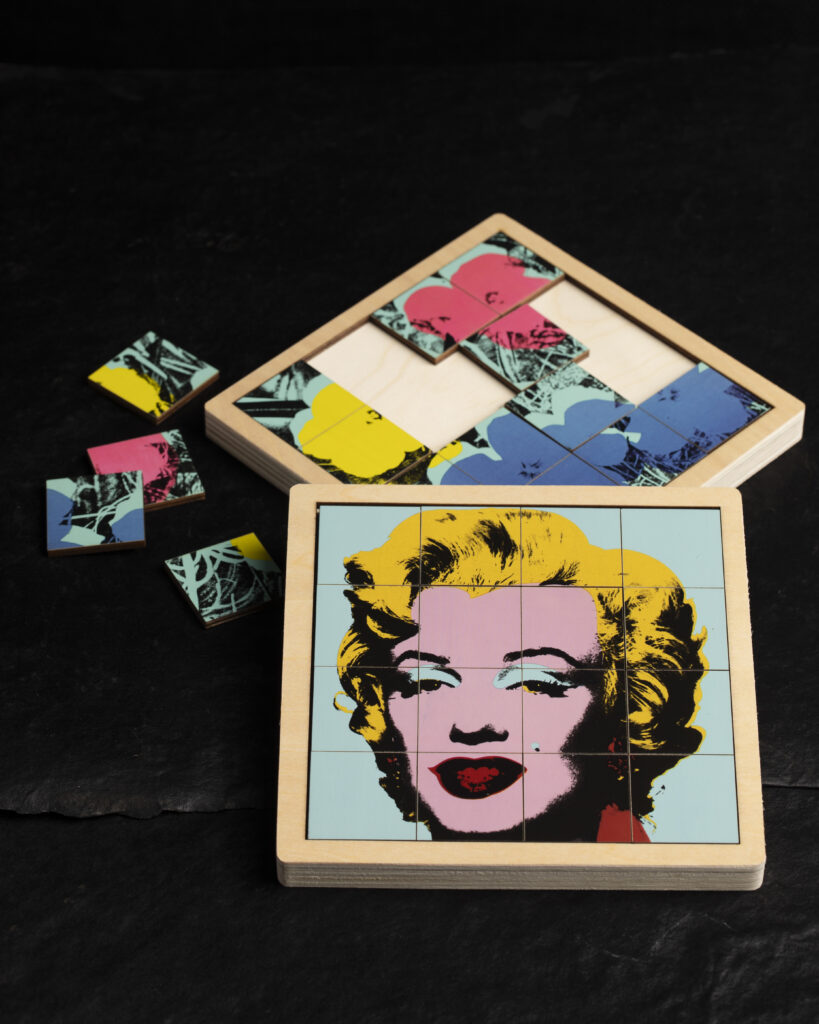 A sliding puzzle of Warhol's Marilyn Monroe painting on a table.