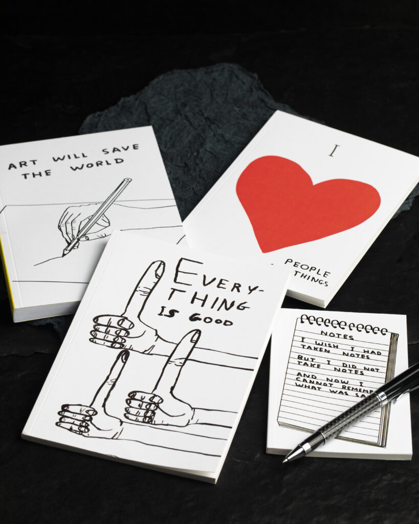 Four white notebooks of varying sizes with hand drawn hearts and images on the front.