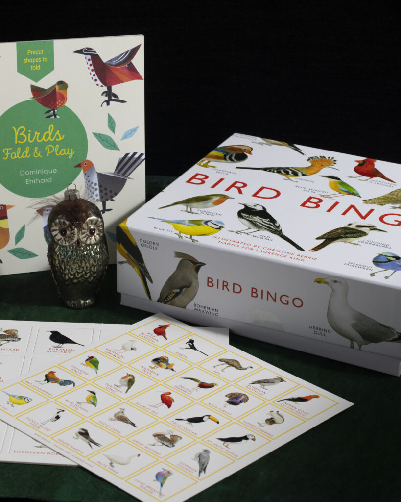 A bird bingo game with bird sheets is laid out on a black table.