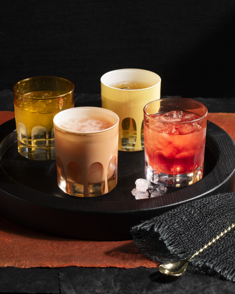 Four cocktail glasses filled with drinks on a tray.