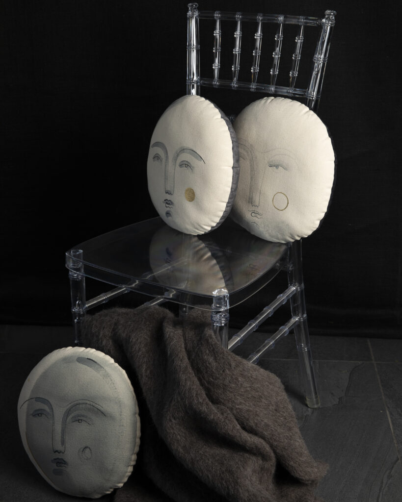 Three moon face pillows placed on a chair.