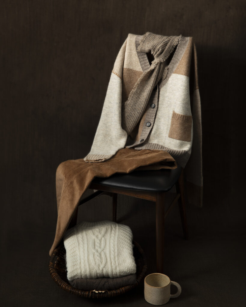 A tan and brown collection of a sweater, scarf, and pants on a chair.