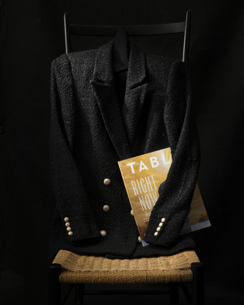 A black blazer with gold embellishments with a TABLE Magazine print issue under the sleeve.