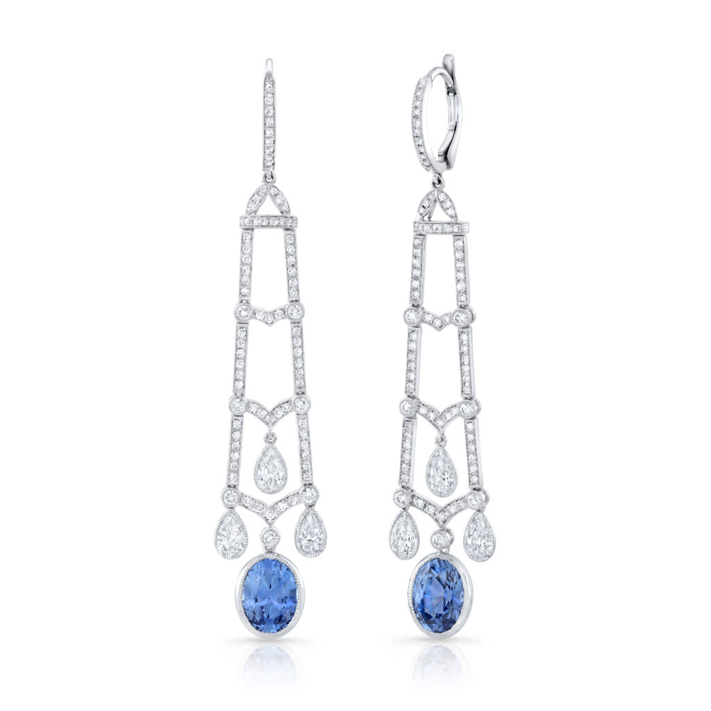 Silver chain links and blue sapphire earrings in front of a white background.